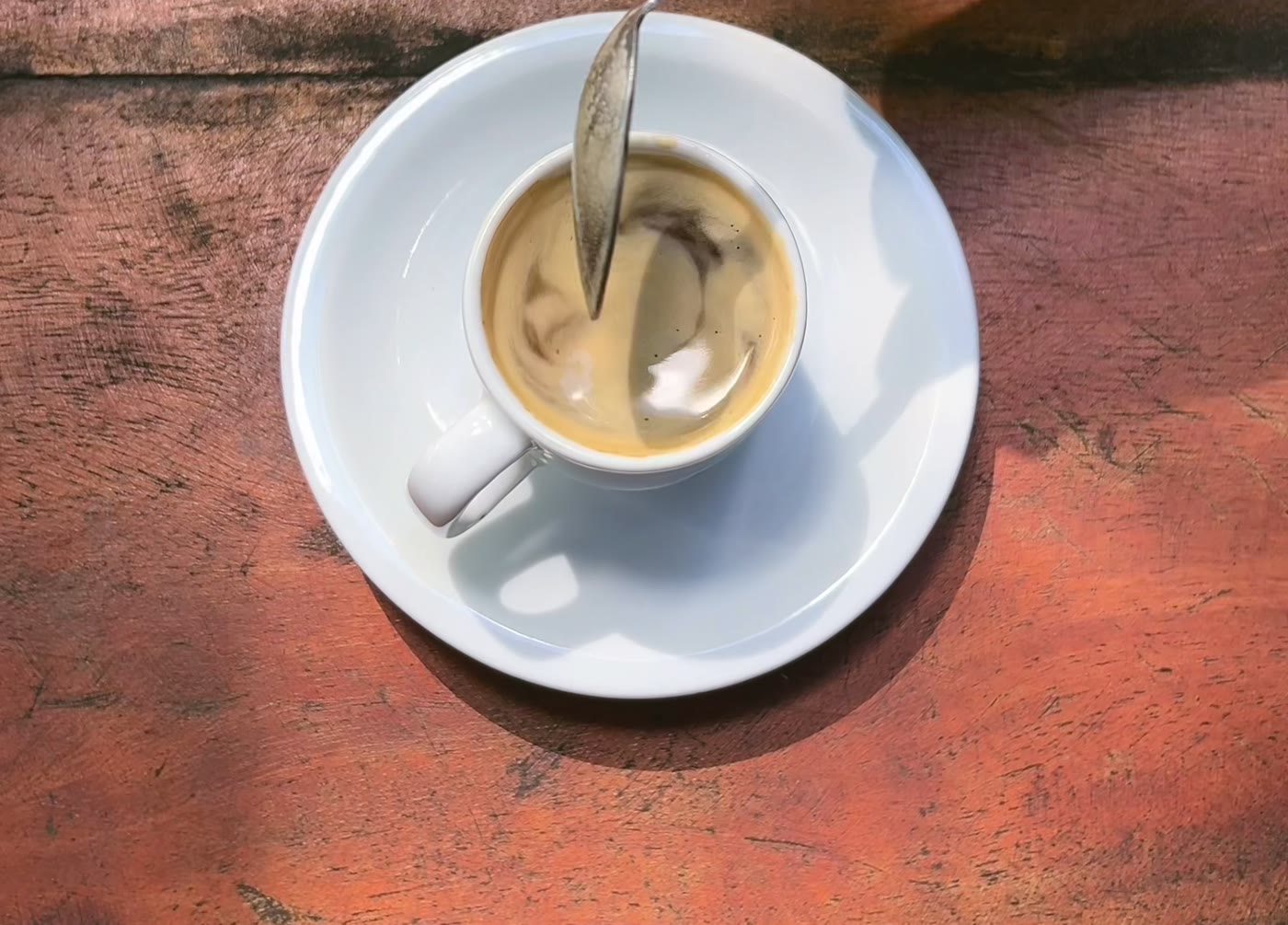 Xícara de café sobre a mesa de madeira antiga do Terraço, na luz da manhã.